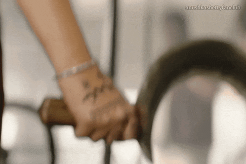a close up of a person 's hand holding a sword with the words anushkashetty fanclub written on the bottom