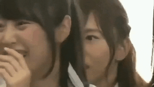 two young women are standing next to each other and laughing together .