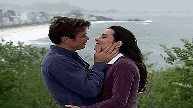 a man and a woman are kissing in front of a city
