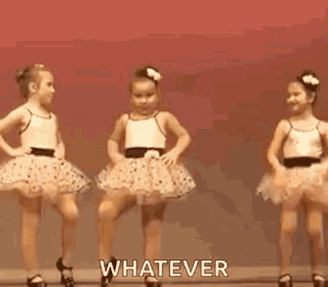 a little girl in a white dress is dancing with her hands in the air and says `` whatever '' .