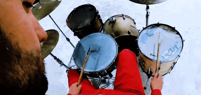 a man in a red shirt is playing drums