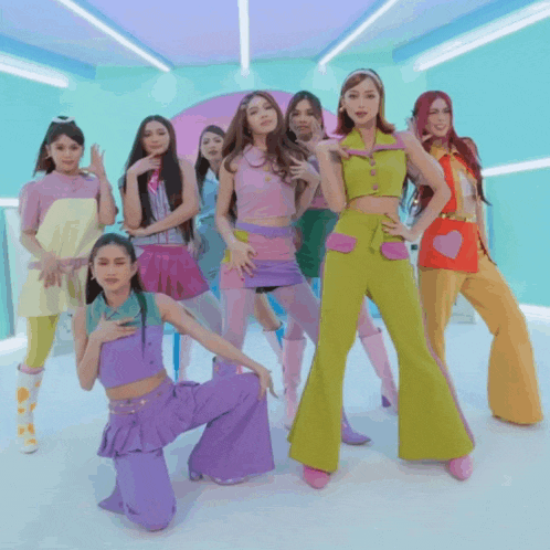 a group of young women in colorful outfits are dancing together