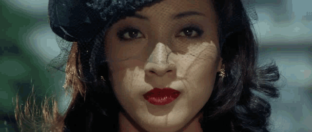 a close up of a woman 's face with red lips and a black hat