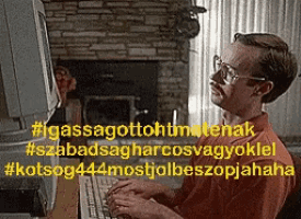 a man with glasses is typing on a computer