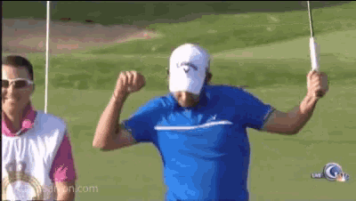 a man in a blue shirt and white hat is holding a golf club in his hand on a golf course .