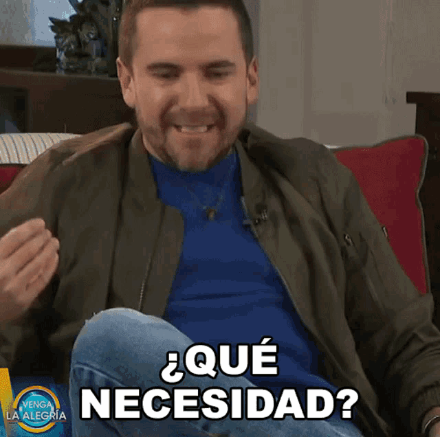 a man sitting on a couch with the words " que necesitad " on the bottom right