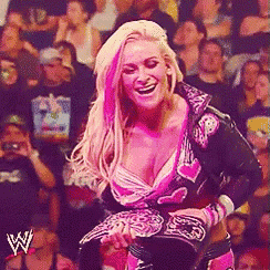 a woman in a pink and black outfit is holding a wrestling belt .