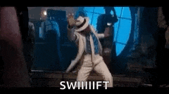 a man in a white hat is dancing in a dark room with the words swift written on the screen .