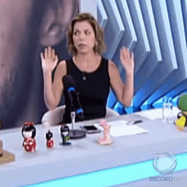 a woman is sitting at a table with a microphone and a sign that says recordtv