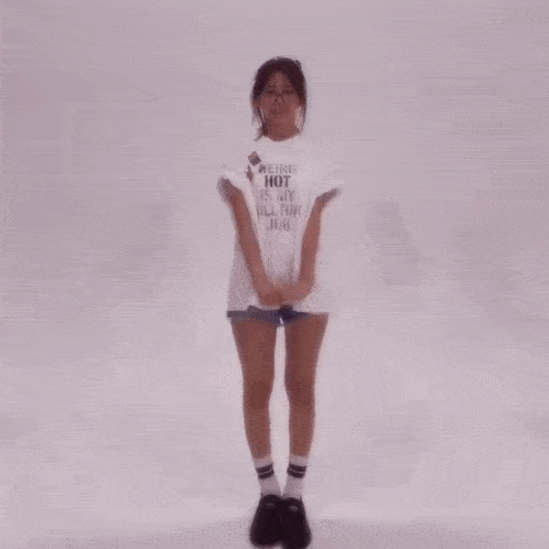 a girl wearing a white shirt that says " not a very tall girl " is surrounded by other girls