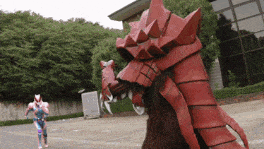 a person in a superhero costume is running towards a large red monster