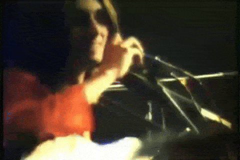 a man is playing a violin in a dark room while wearing sunglasses .