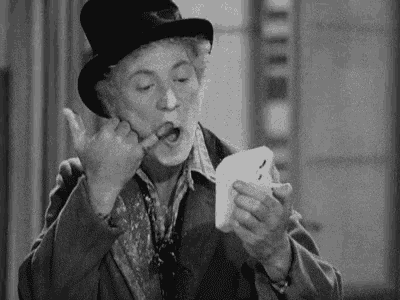 a black and white photo of a man in a top hat brushing his teeth .