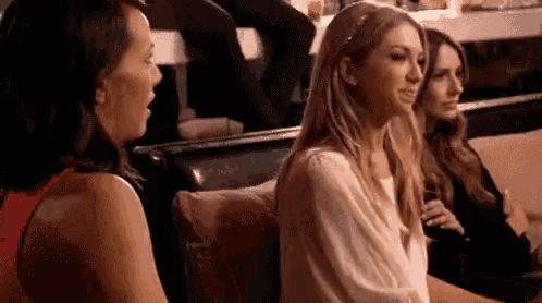 a group of women are sitting on a couch talking to each other in a restaurant .