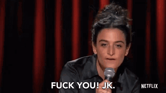a woman is holding a microphone on a stage and saying `` fuck you jk '' .