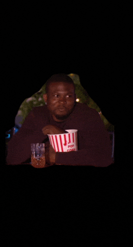 a man is holding a bucket of popcorn and a glass of beer