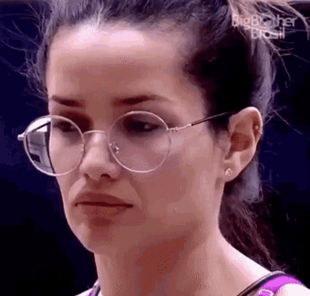 a close up of a woman wearing glasses with a ponytail .