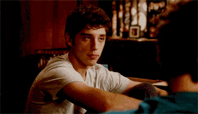 a young man in a white shirt is sitting down
