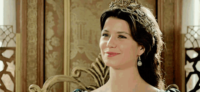 a woman wearing a tiara and earrings smiles