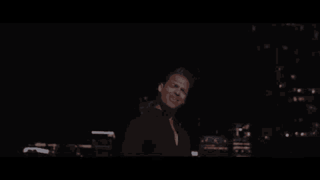 a man is standing in front of a city at night .