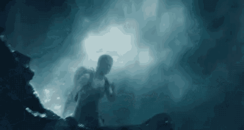 a woman is swimming underwater in a dark cave with a backpack .