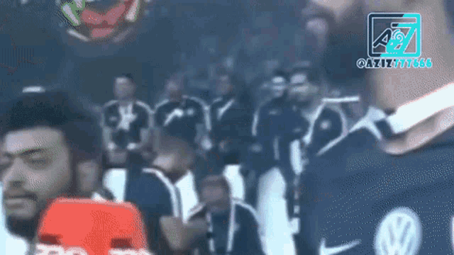 a blurry picture of a group of people with a volkswagen logo on their shirt