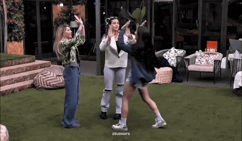a group of women are dancing on a lush green lawn