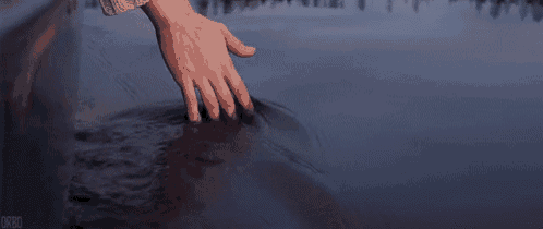 a close up of a person 's hand touching a body of water .