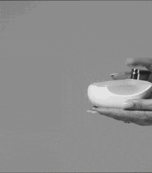 a person is holding a bottle of perfume in their hand .