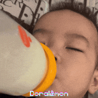 a baby drinking from a bottle with doraemon written on the bottom of the image