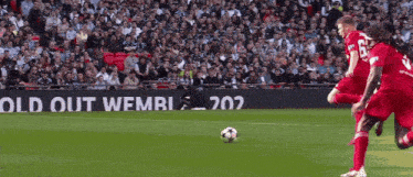 a soccer player kicking a ball in front of a sign that says old out wembley 202