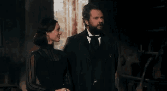 a man and a woman are standing next to each other in a dark room and smiling .