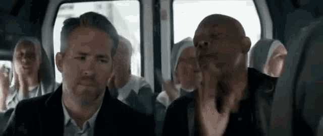 a man and a woman are sitting in a bus with a group of people .