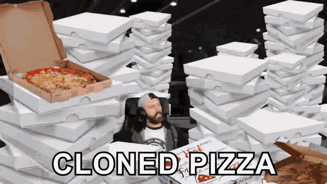 a man sits in front of a stack of pizza boxes with the words " cloned pizza " written on the bottom