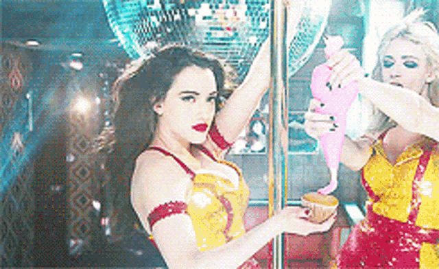 two women are standing on a pole one is holding a cup