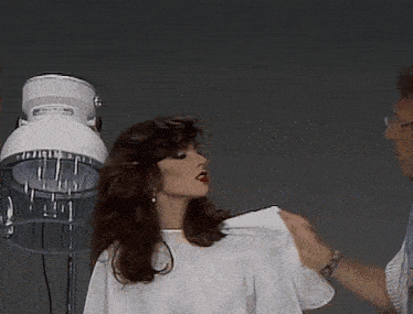 a woman is getting her hair blow dried by a man in a white shirt