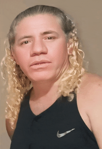 a man with long curly hair wears a black nike tank top