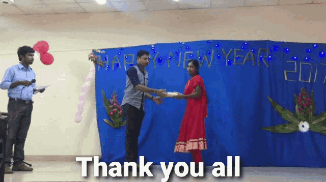 a man giving a woman a gift in front of a blue wall that says happy new year 2017