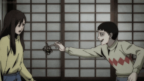 a man and a woman are standing next to each other and the man is holding a spider