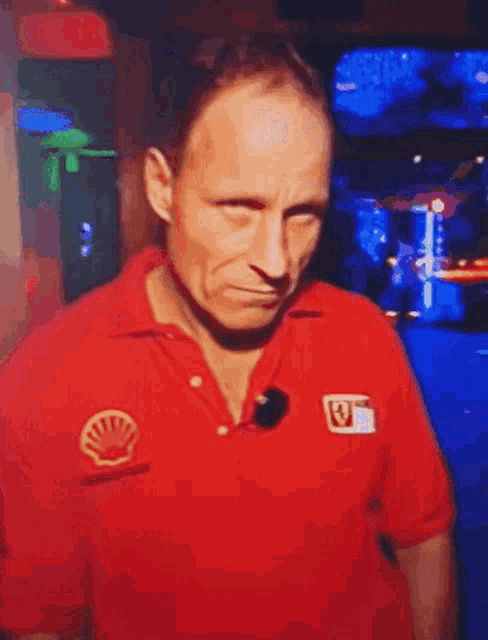 a man in a red shirt with a shell logo on it