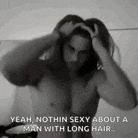 a shirtless man with long hair is standing in front of a mirror .