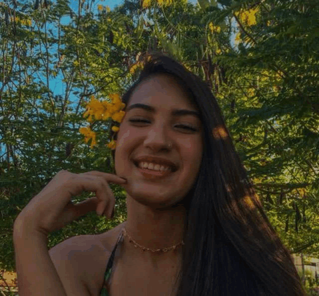 a woman is holding a yellow flower in her hair and smiling .