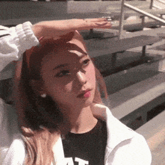 a woman is standing in front of a set of stairs holding her hand up to her forehead .