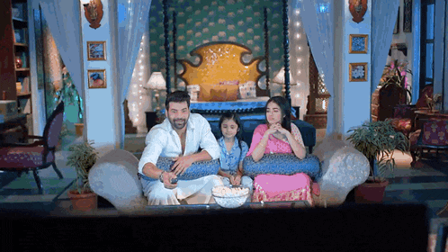 a family is sitting on a couch watching television