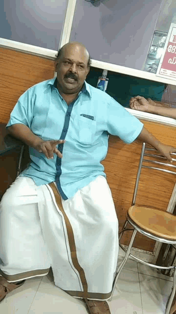 a man in a blue shirt sits on a chair in front of a sign that says no smoking