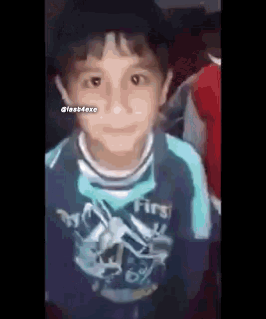 a young boy wearing a blue shirt that says first is standing in a crowd .