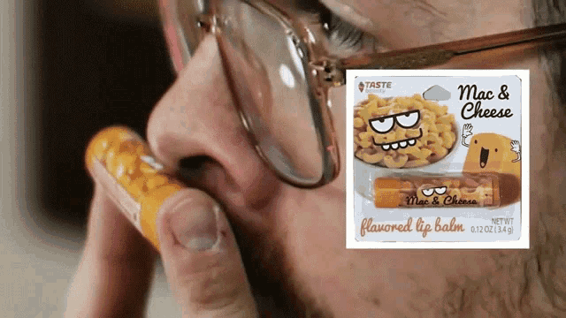 a man wearing glasses holds a tube of mac and cheese lip balm