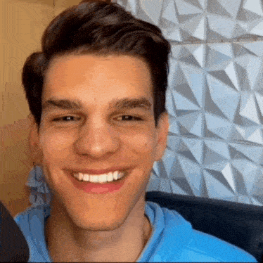 a young man in a blue hoodie is smiling for the camera
