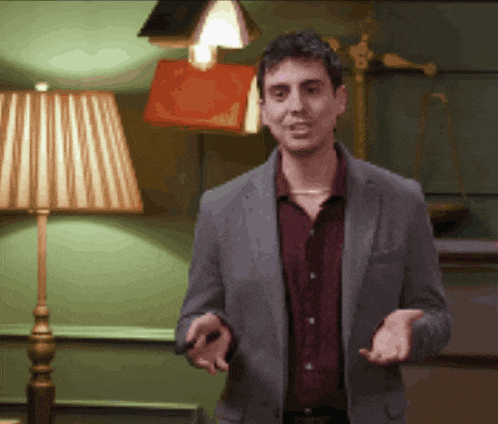 a man in a suit stands in front of a lamp and a book
