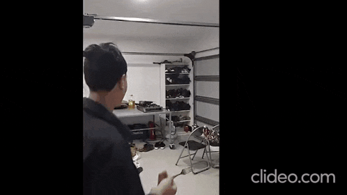 a man is standing in a garage with a vacuum cleaner and a table .
